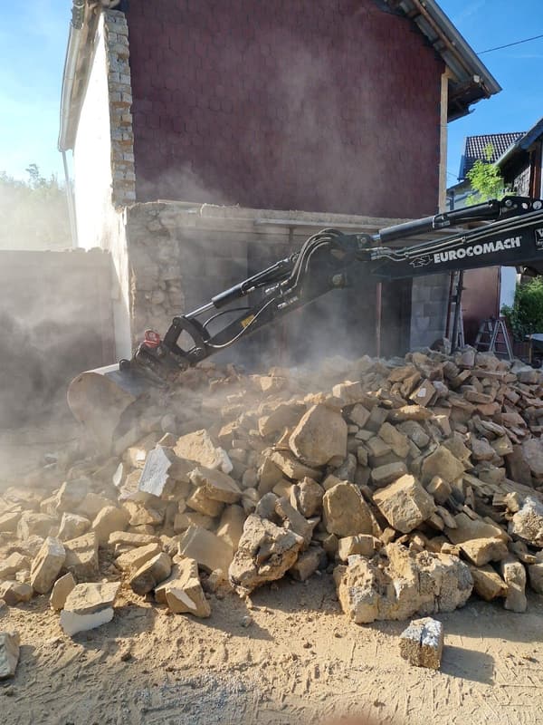 Minibagger räumt Bruchstein-Schutt eines abgerissenen Anbaus